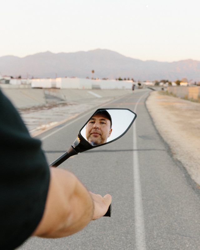 Daniel Tonkopiy's face reflected in a bike mirror on a road in Los Angeles
